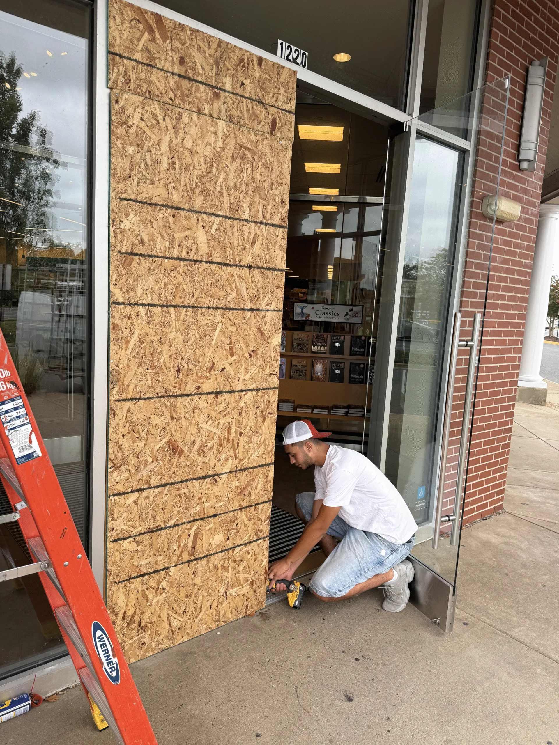 Emergency board-up service securing a storefront with plywood after glass damage. Glass repair by technician | American Glass and Door
