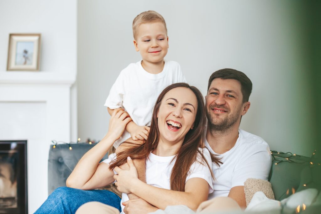 Happy family near Sliding Glass Doors. Smiling parents with child in modern home. Natural light and comfort | American Glass and Door