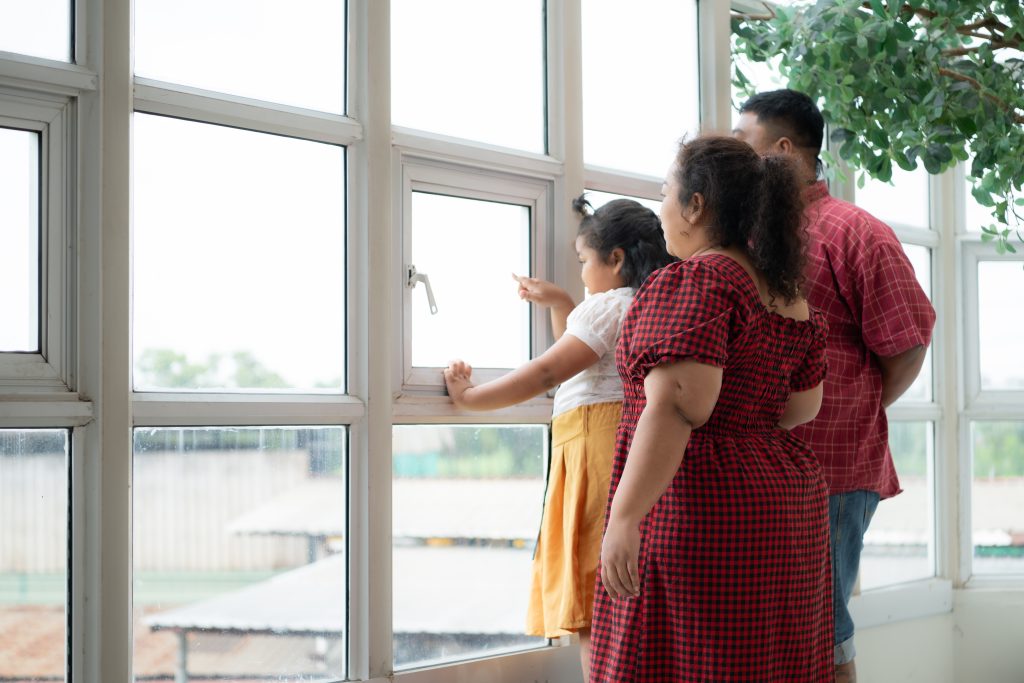 Family looking through new Commercial Window Replacement, enjoying the view from their energy-efficient windows | American Glass and Door