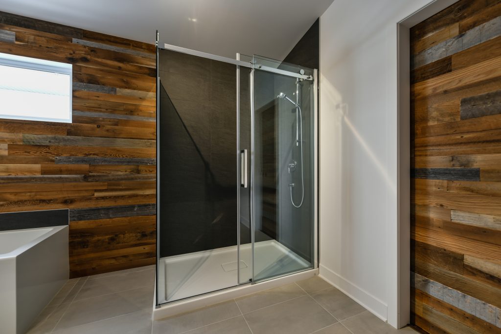 Sleek sliding glass shower door repair design with rustic wood paneling for a modern bathroom aesthetic | American Glass and Door